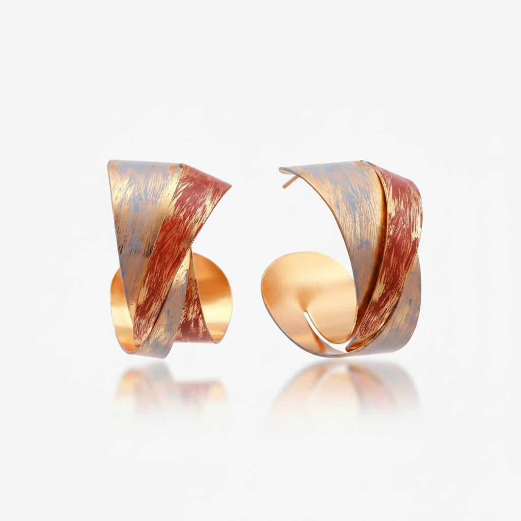 Sculptural gold-plated hoop earrings with diagonal purple and coral enamel stripes in twisted ribbon design