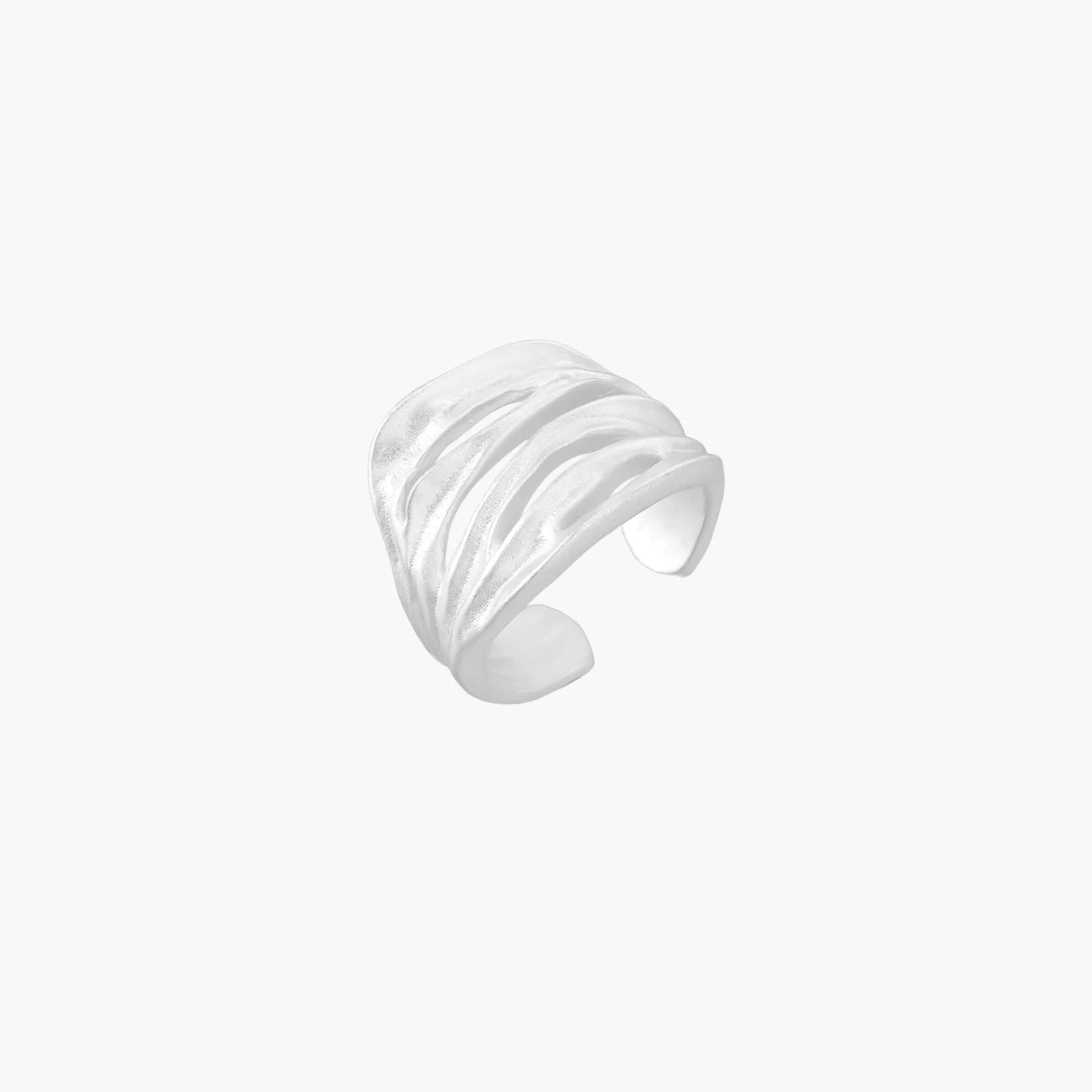 Wide sterling silver cuff ring with flowing wave patterns creating dimensional texture against cream background