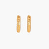 Gold-toned hoop earrings with hammered dimpled texture and post closure on cream background
