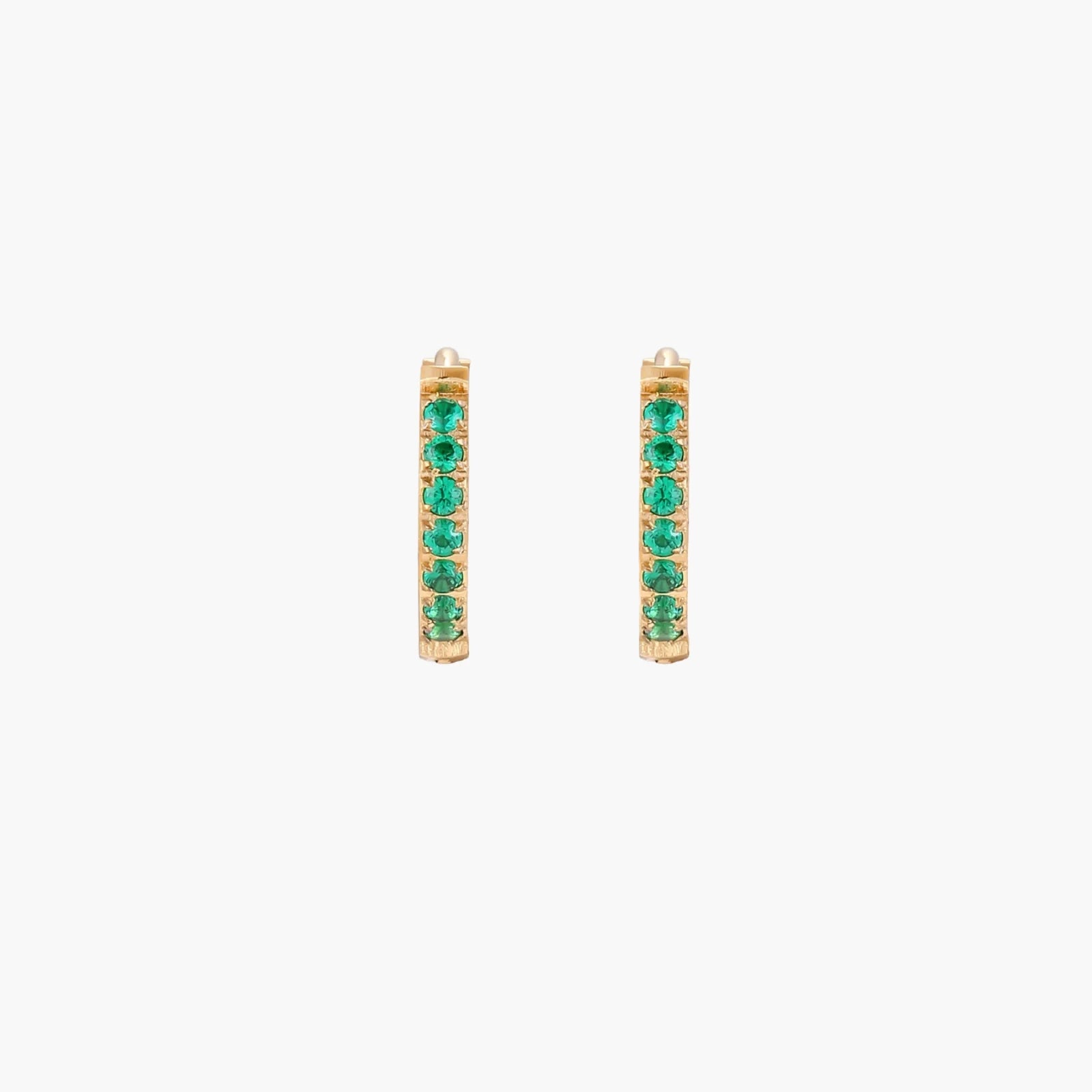 Pair of small gold huggie hoop earrings with bright green cubic zirconia stones on cream background